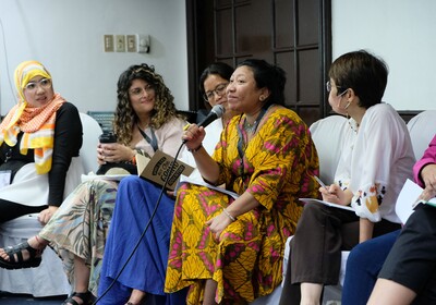 Eine Kolumbianierin spricht am Mikrofon, während Frauen aus den Philippinen ihr zuhören