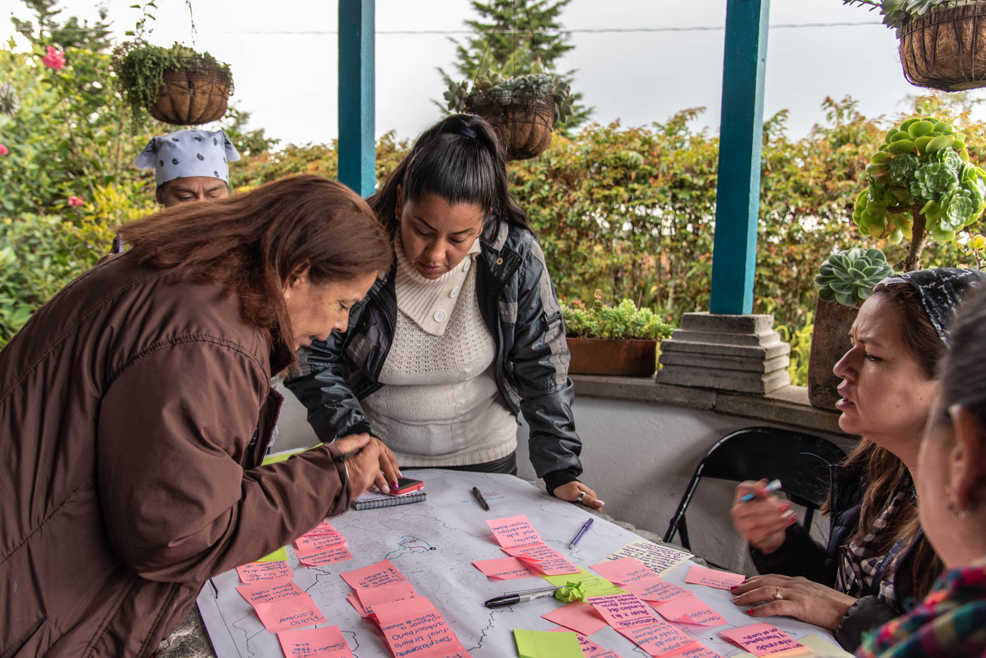 Diverse Frauen sitzen am FrauenFriedensTisch in Kolumbien zusammen und diskutieren unter anderem Notizen auf Post-its.