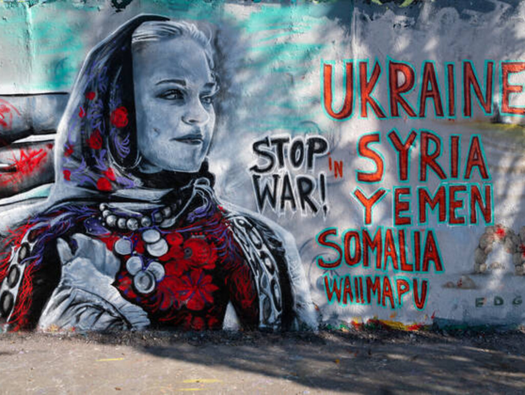 wall with anti-war graffiti and picture of a women with a headscarf