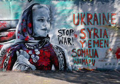 wall with anti-war graffiti and picture of a women with a headscarf